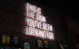 A large Neon sign on a brick wall with the words "This is the sign you've been looking for"